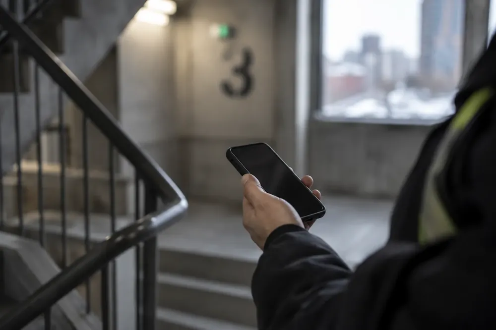 Staff member holding a phone in a stairwell
